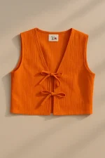 Turuncu renkli, iki fiyonklu, kolsuz keten kadın yeleği – düz arka plan üzerinde sergilenmiş.